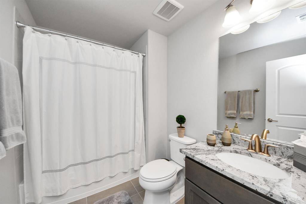 This bathroom features a modern design with a granite countertop, sleek fixtures, and a neutral color palette.
