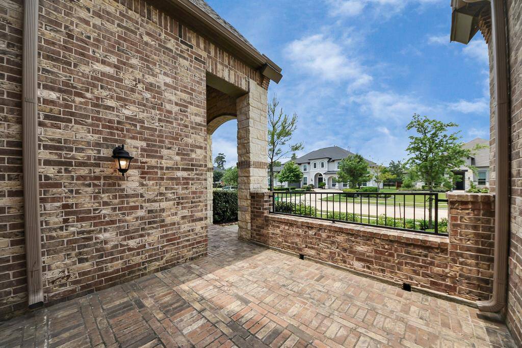 Charming brick front patio with elegant archway, perfect for morning coffee or greeting guests.