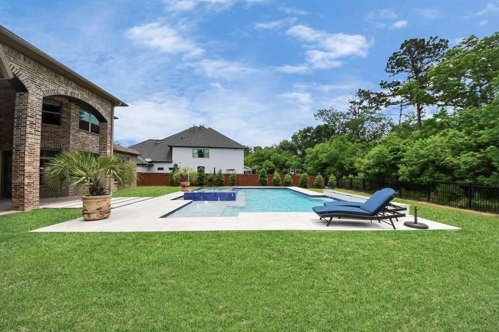 This backyard oasis features a stunning modern pool, lush greenery, and a pristine lawn, offering exceptional privacy with no rear neighbors.