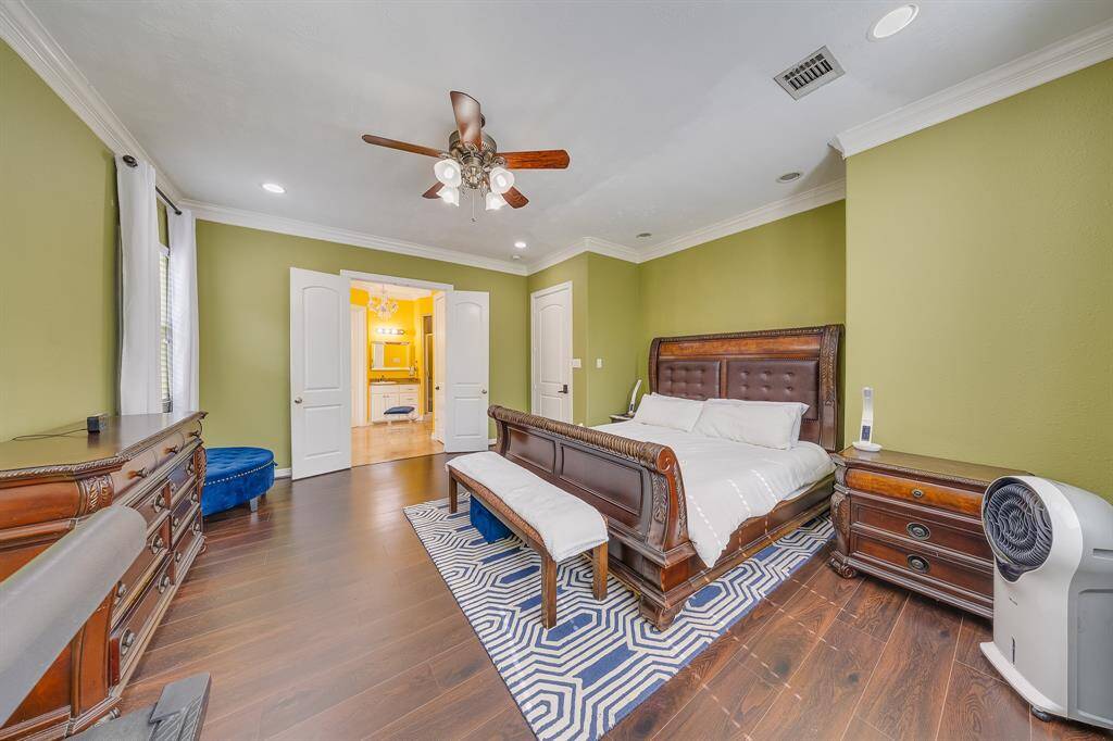 Serene primary bedroom with soft green accents, large windows, and cozy ambiance for restful nights and peaceful mornings.