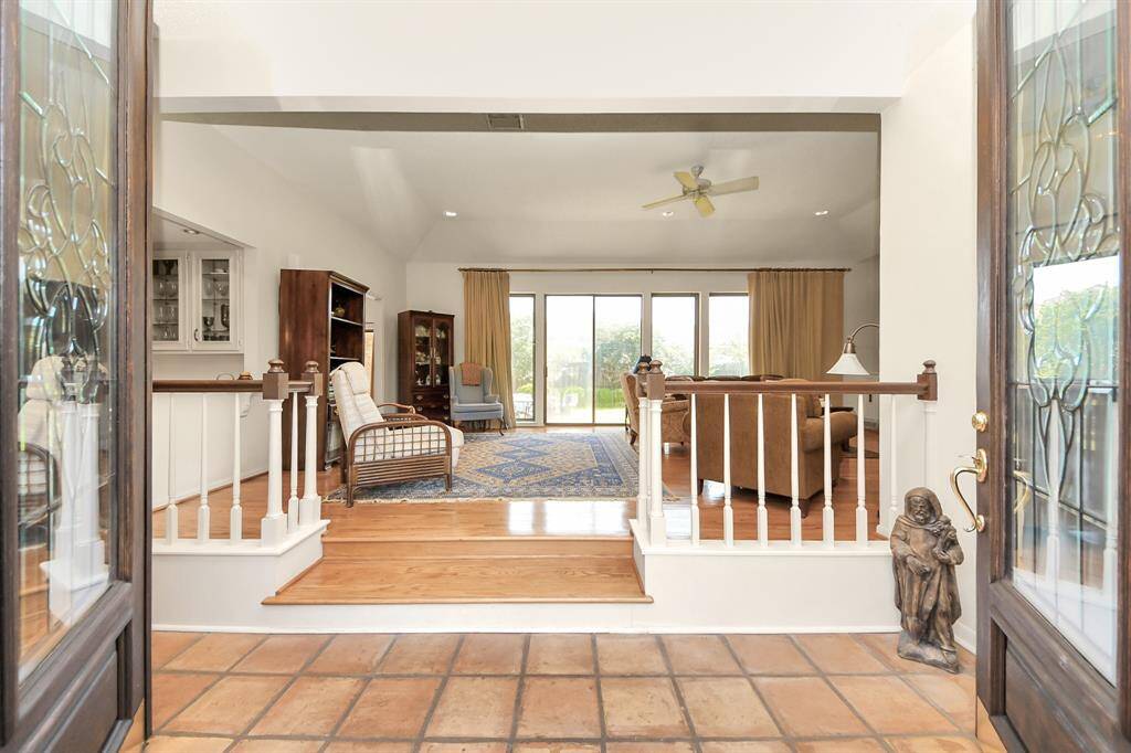 Eight foot leaded glass doors lead into a grand living space with vaulted ceilings, overlooking the lush backyard.