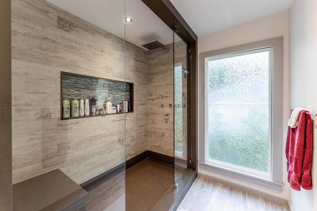 Spa vibes only—this oversized walk-in shower features a rainfall head, built-in bench, and sleek tile accents.