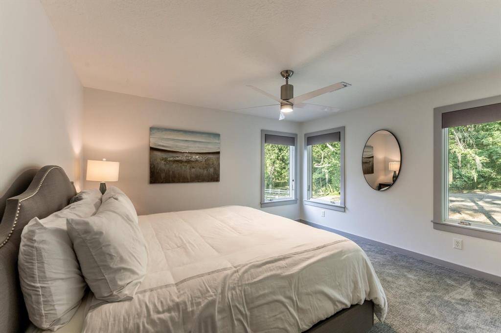 Guest bedroom with tranquil views, soft carpet underfoot, and wraparound windows that bring the outdoors in—your visitors may never want to leave!