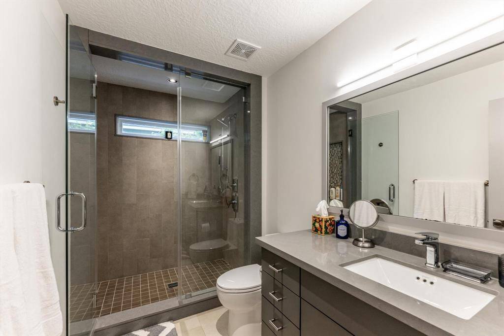 Shared by the upstairs guest rooms, this stylish bath features a sleek quartzite vanity, expansive walk-in shower, and thoughtful modern finishes throughout.