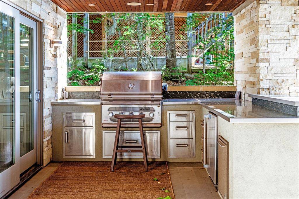 Fire up the fun—this built-in outdoor kitchen is fully equipped with a premium grill, fridge, and sleek stainless and quartz countertops with the dining table being marble, perfect for lakeside cookouts and alfresco vibes.