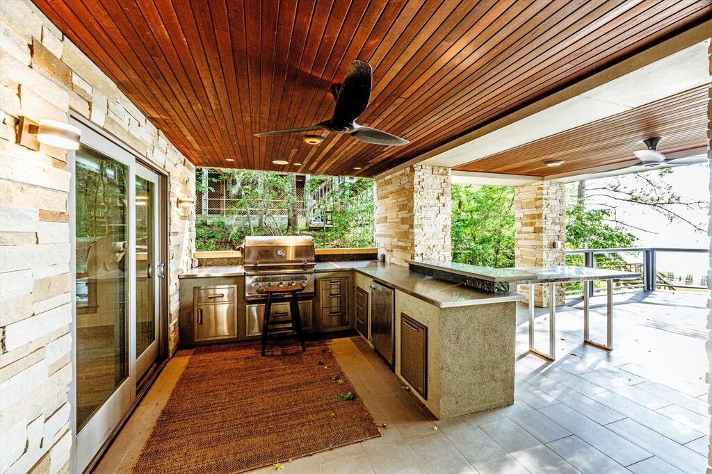 This covered outdoor kitchen takes entertaining to the next level—grill, chill, and dine with lake views and a breeze, all under the warm glow of IPE wood-paneled ceilings and built-in top notch fans.