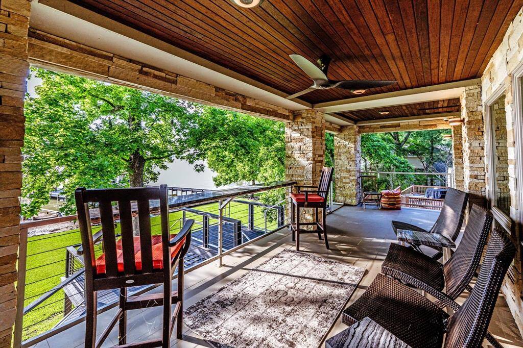Unwind in style on this expansive tile floored deck with IPE wood ceiling—where lake views, ceiling fans, and cozy seating make every moment feel like a vacation.