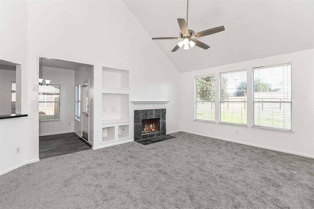 Spacious living room with vaulted ceilings, abundant natural light from large windows, and a cozy fireplace. Adjoining the living area is a dedicated dining space, perfect for gatherings. Enjoy modern finishes and a seamless flow to the backyard.