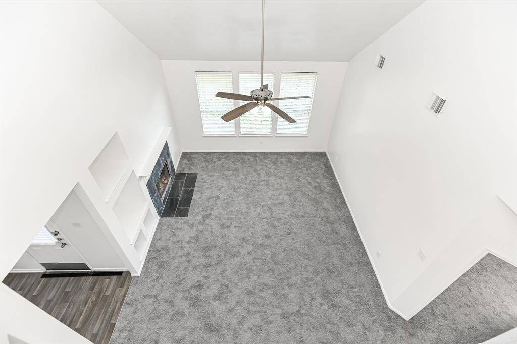 This elegant living room features high ceilings, a cozy fireplace, and abundant natural light from large windows. The neutral tones and open layout offer a perfect canvas for your personal touch.