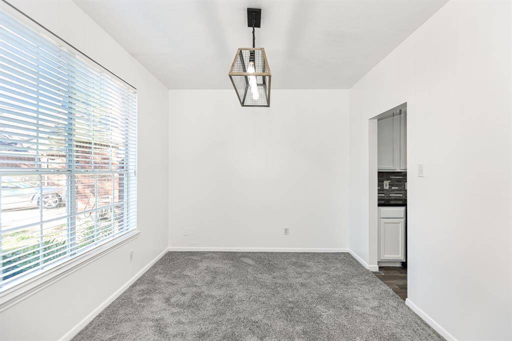 Bright and inviting room with large windows, plush carpeting, and modern lighting. Perfect for a cozy dining area or home office. Adjacent to the stylish kitchen.