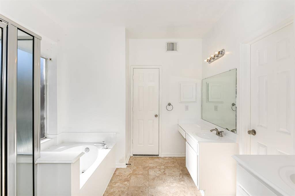 Bright and spacious bathroom featuring a luxurious soaking tub, elegant vanity, and modern fixtures. Abundant natural light creates a serene and inviting atmosphere.