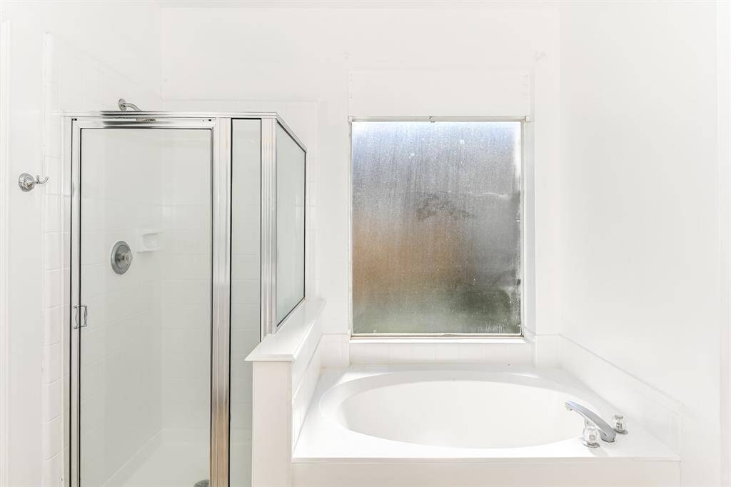 Experience ultimate relaxation in this bright bathroom featuring a sleek glass shower and a luxurious soaking tub, perfect for unwinding after a long day.
