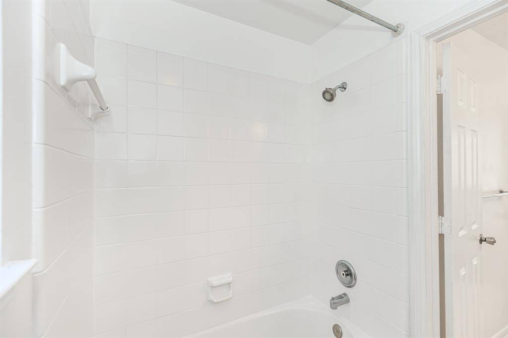 This bathroom offers a bright and clean look with fresh white tiles and a classic shower-tub combination, perfect for relaxing and unwinding.