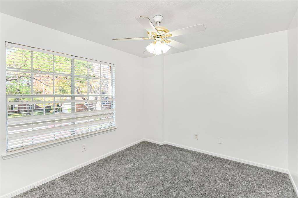 Bright and inviting room with fresh carpeting, a large window for natural light, and a ceiling fan for comfort. Perfect for a cozy retreat or home office.