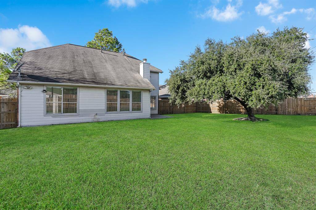 Spacious backyard with lush green lawn and a charming mature tree, perfect for relaxation and outdoor activities. Enjoy privacy with a secure wooden fence. Ideal for families and entertaining.