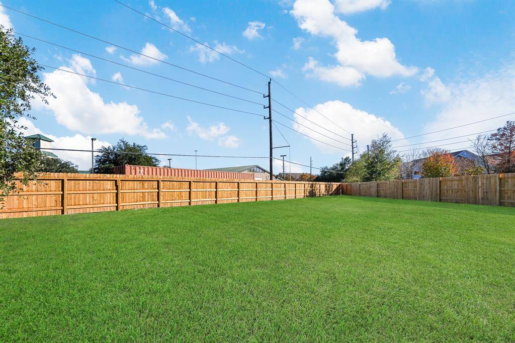 Expansive and beautifully maintained backyard, perfect for outdoor activities and relaxation. Enjoy privacy with a sturdy wooden fence, all under a clear, sunny sky. Ideal for family gatherings and creating your own outdoor oasis.