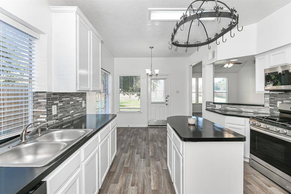 Modern kitchen with sleek black countertops, stainless steel appliances, and a stylish backsplash. Bright and inviting, this space is perfect for cooking and entertaining.