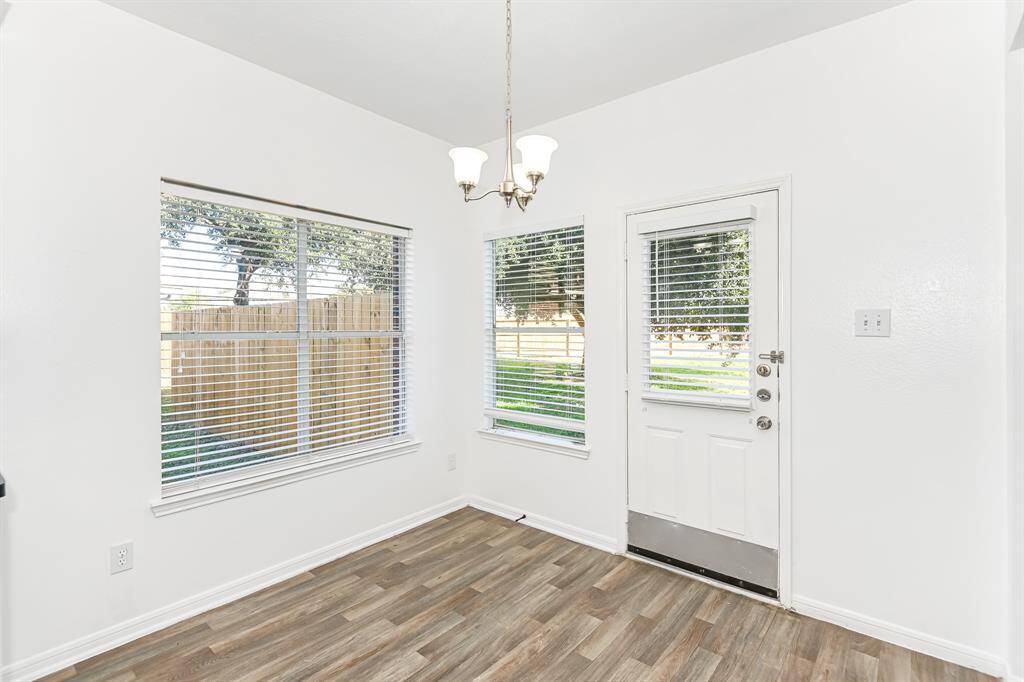 Bright and inviting dining area with large windows offering serene views of the backyard. Features a stylish light fixture and easy access to the outdoor space, perfect for entertaining or enjoying a quiet meal.