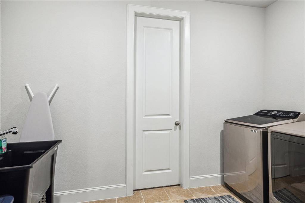 Partial view of the large laundry room with direct access to the Primary closet.  Utility sink added with inset scrub section.  Full-sized washer and dryer included.