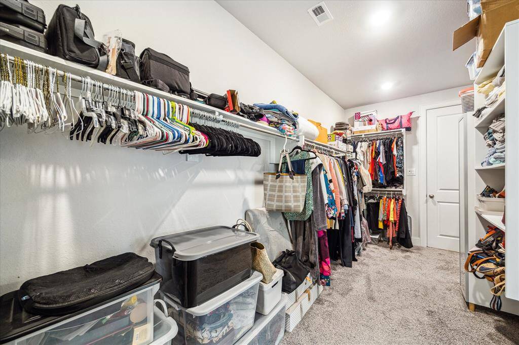 Primary closet view back towards laundry room, highlighting the amount of hanging space and storage space above; ideal for adding pull downs for even more additional hanging space for seasonal items.