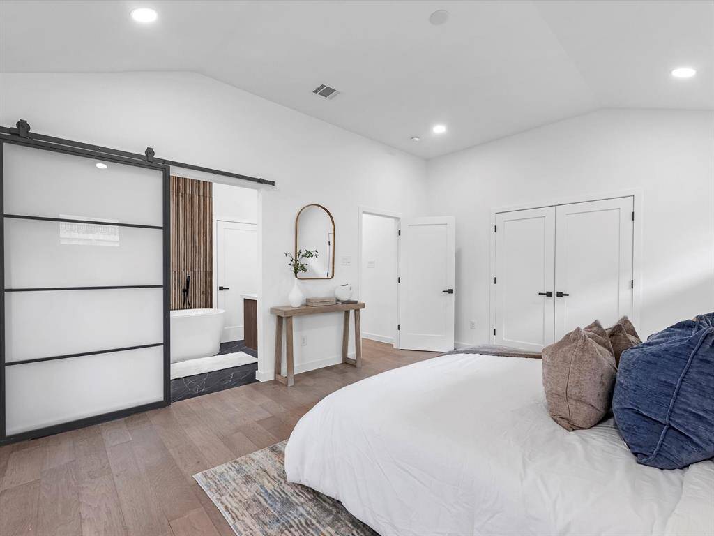 View of the primary bathroom with iron/glass bard door from the bedroom