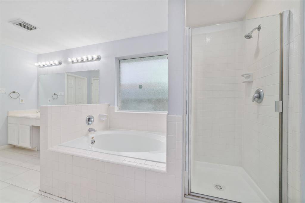 Primary en-suite bathroom with large soaking tub and separate standing shower