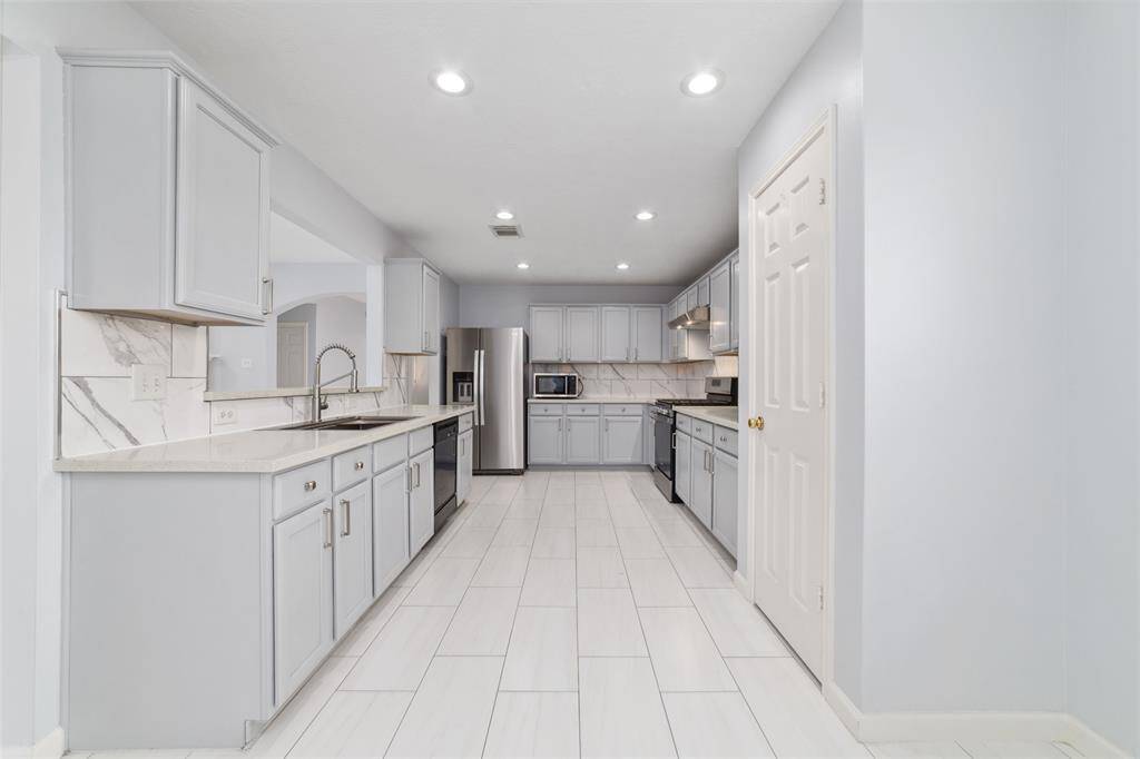 Updated kitchen with stainless steel appliances, large single basin workstation sink, quartz countertops, breakfast bar, and walk in pantry