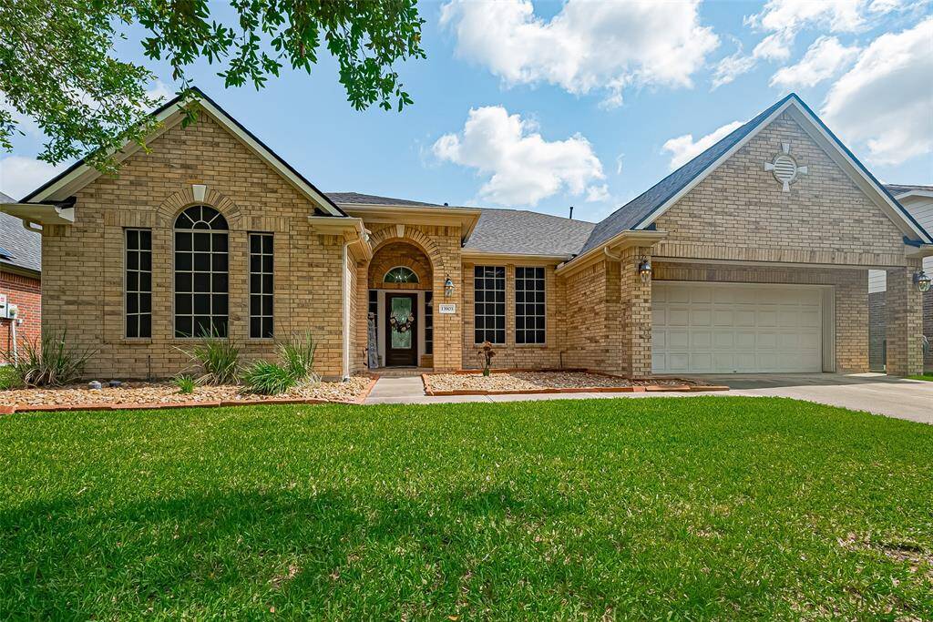This charming brick home features a well-maintained lawn, a three-car tandem garage, and large arched windows that bring in plenty of natural light. It offers a welcoming entryway and is situated on a quiet street in a desirable neighborhood.