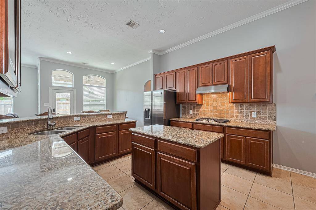 Spacious kitchen with granite countertops, a central island, and ample cabinet storage, including a spacious pantry. Features stainless steel appliances, tile flooring, and large windows for natural light.