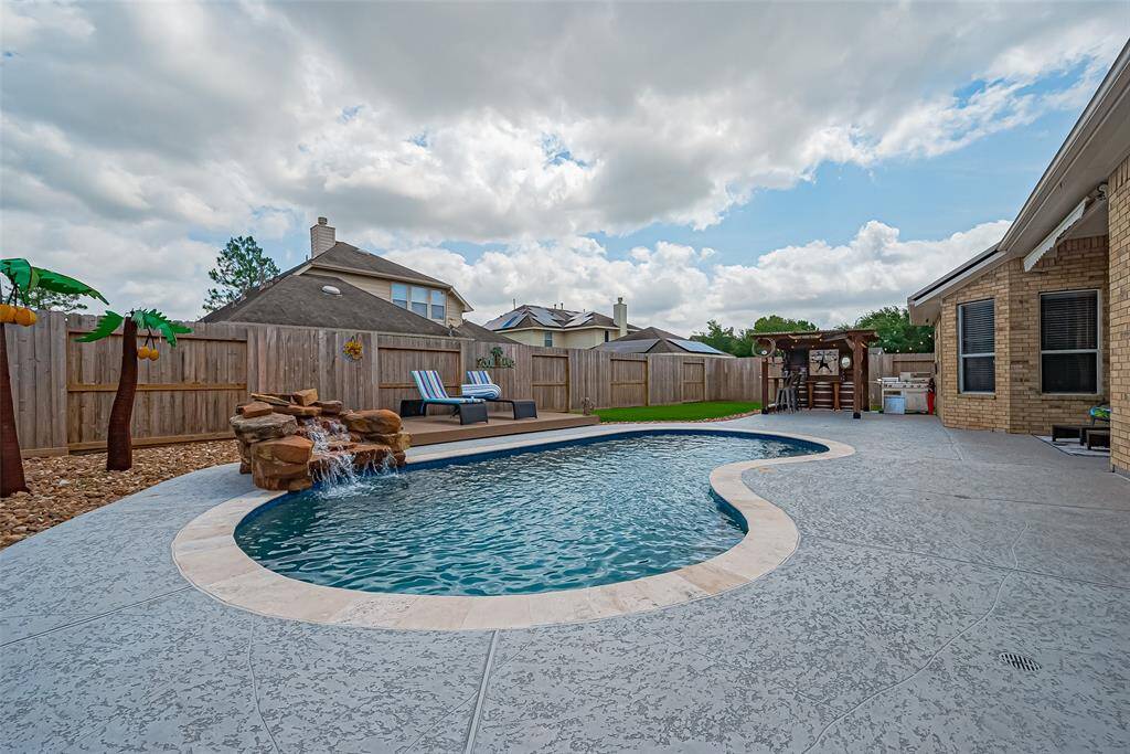 This backyard oasis features a private pool with a rock waterfall, surrounded by a spacious patio—perfect for relaxing or entertaining.