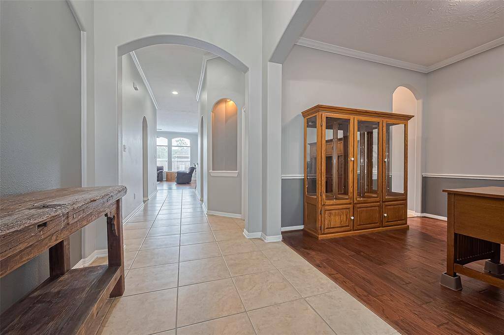 This photo showcases a bright, spacious hallway with tile flooring and graceful archways leading to the main living area. Just off the entry, a versatile flex room offers endless possibilities—create a home office, study, formal dining, or living space to suit your needs.