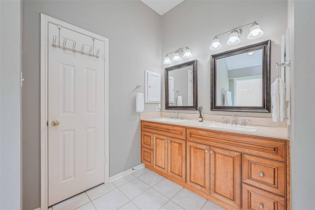 Luxurious en suite bathroom featuring double sinks, elegant mirrors, and ample storage.
