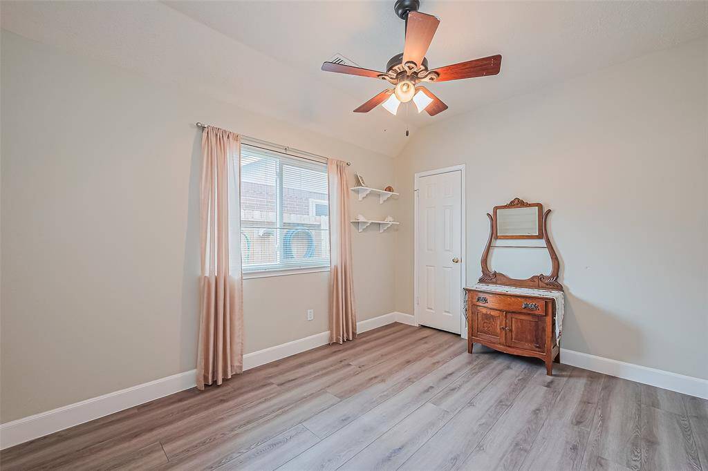 Spacious secondary bedroom with stylish curtains included and elegant hardwood floors.