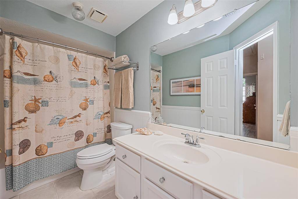 Inviting secondary bathroom with elegant fixtures, ample storage, and a soothing coastal-themed decor.