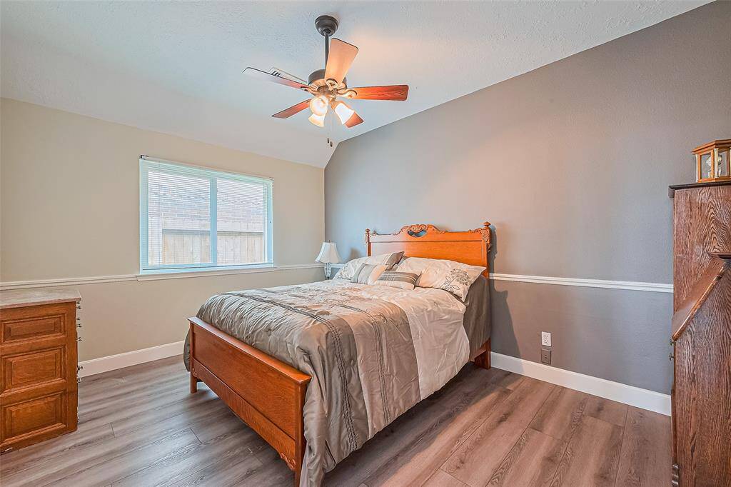 Cozy third bedroom featuring stylish flooring, abundant natural light, and a ceiling fan for added comfort.