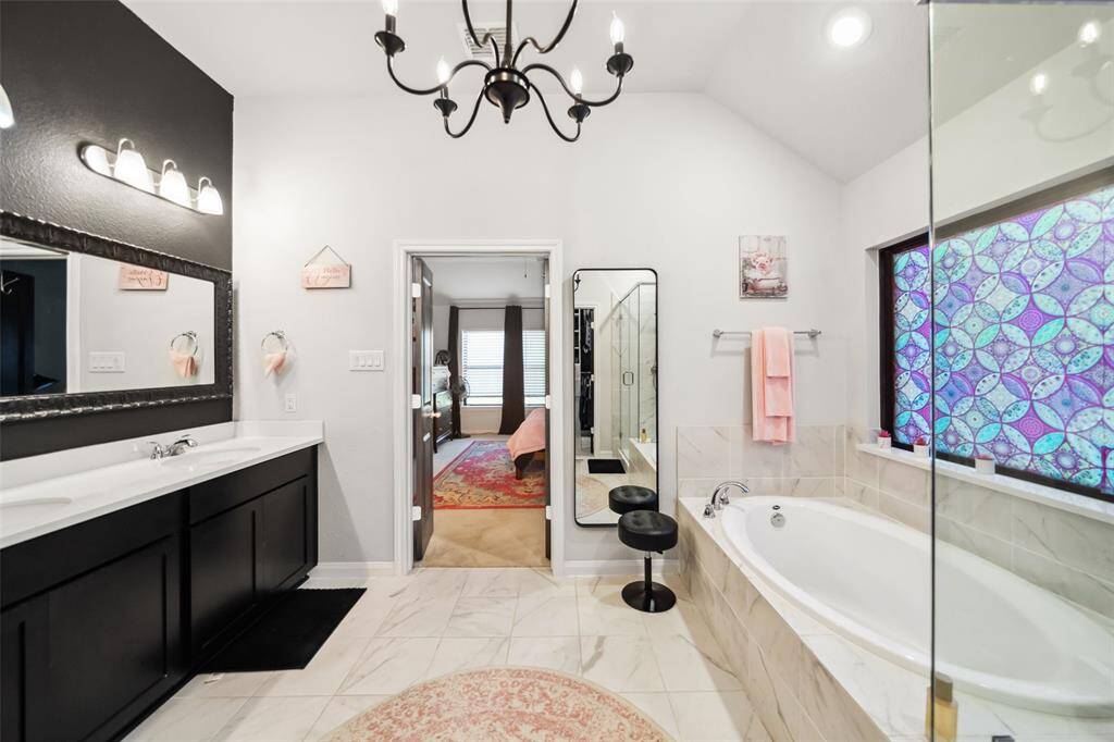 The en suite primary bath has double vanity sinks and a chandelier.