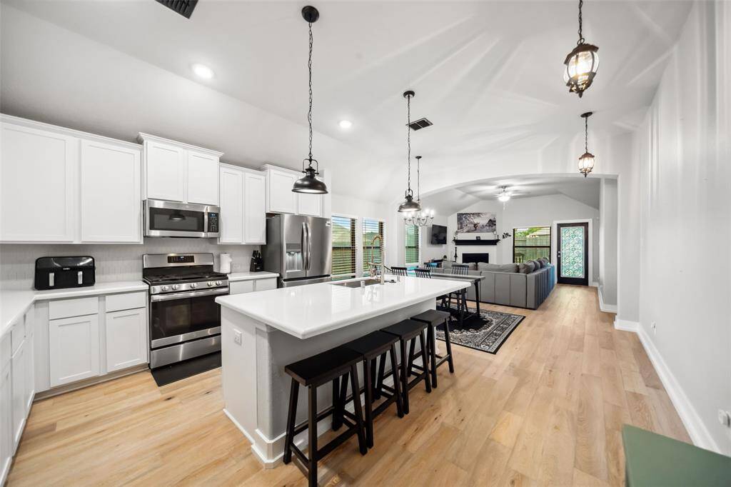A modern kitchen with stainless steel appliances, quartz countertops, and upgraded lighting.