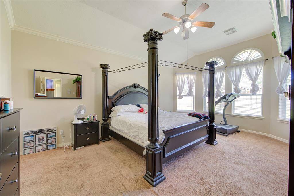 Elegant primary bedroom with high ceiling and large arched windows.