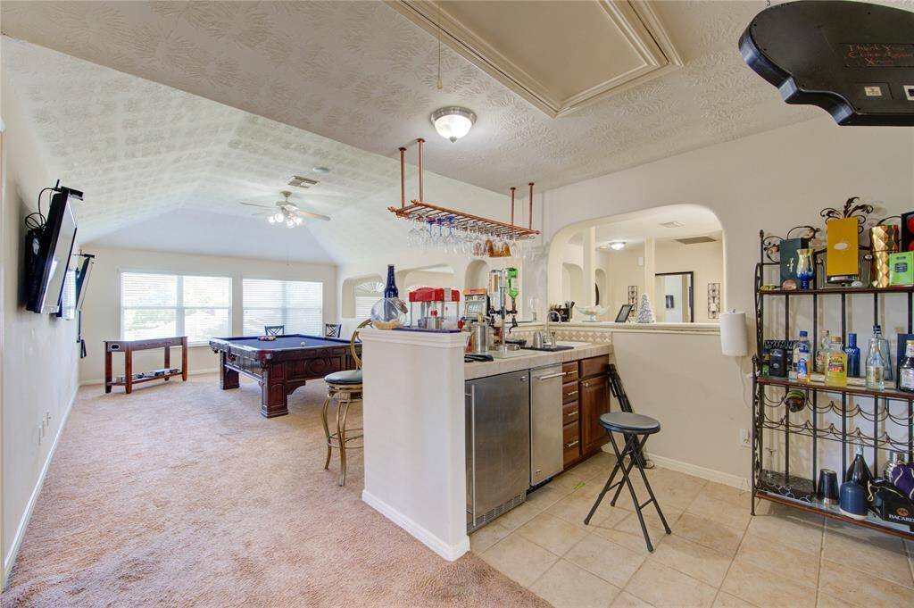 Upstairs game room with built-in bar featuring sink and mini fridge — perfect for entertaining, movie nights, or a hangout space.