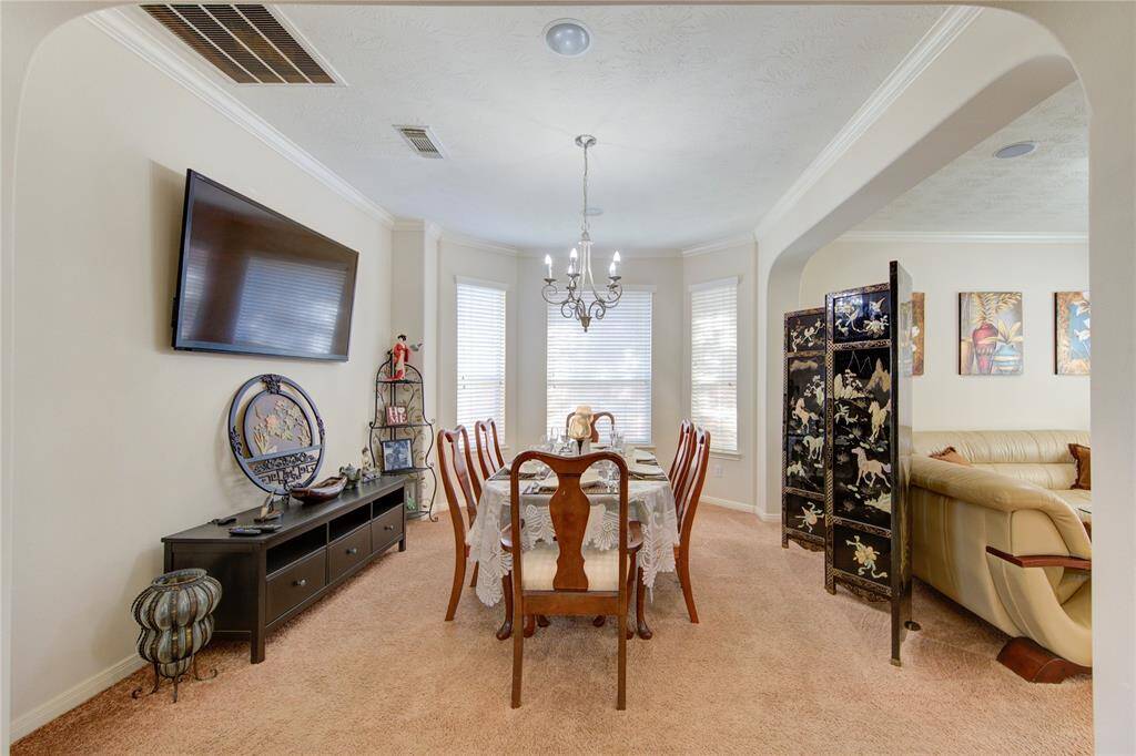 Formal dining area with large windows and crown molding.