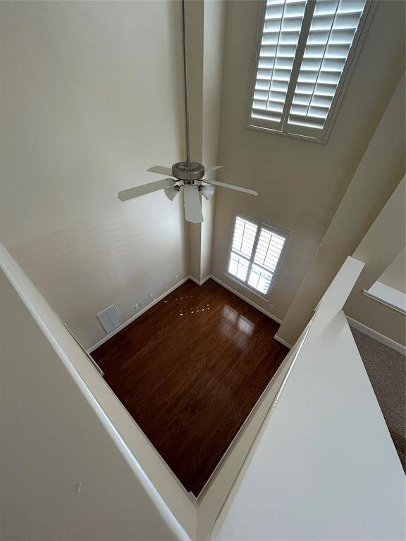 Spacious study with high ceilings and large windows with shutters, allowing plenty of natural light. The hardwood flooring adds warmth, and the room has an open, airy feel.