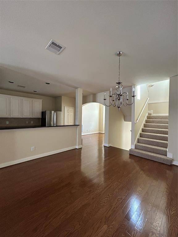 Elegant dining room with gleaming hardwood floors, offering a seamless view into the pristine kitchen featuring stainless steel appliances and modern finishes.