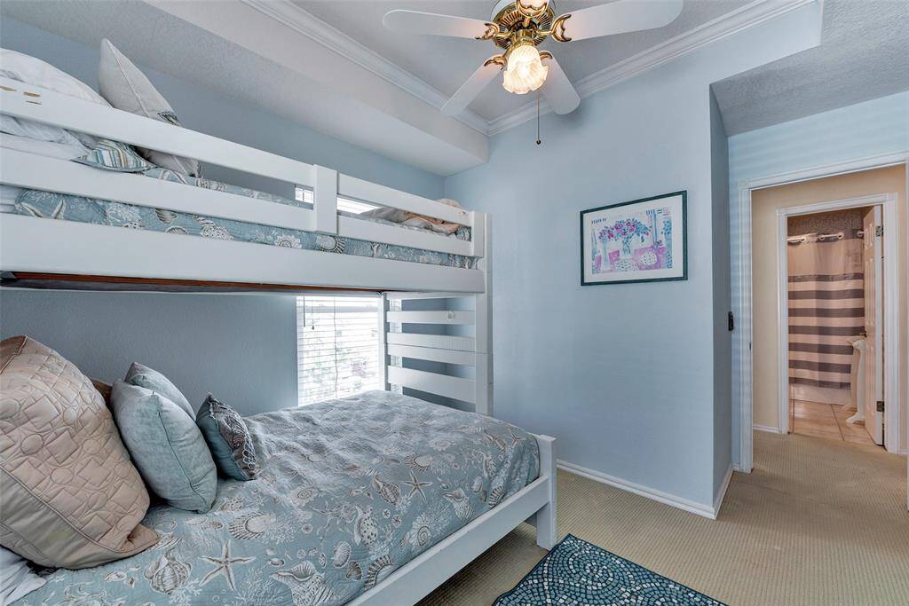 Upstairs bedroom features soft coastal tones, crown molding, and easy access to a full bath. A relaxing space for guests or family