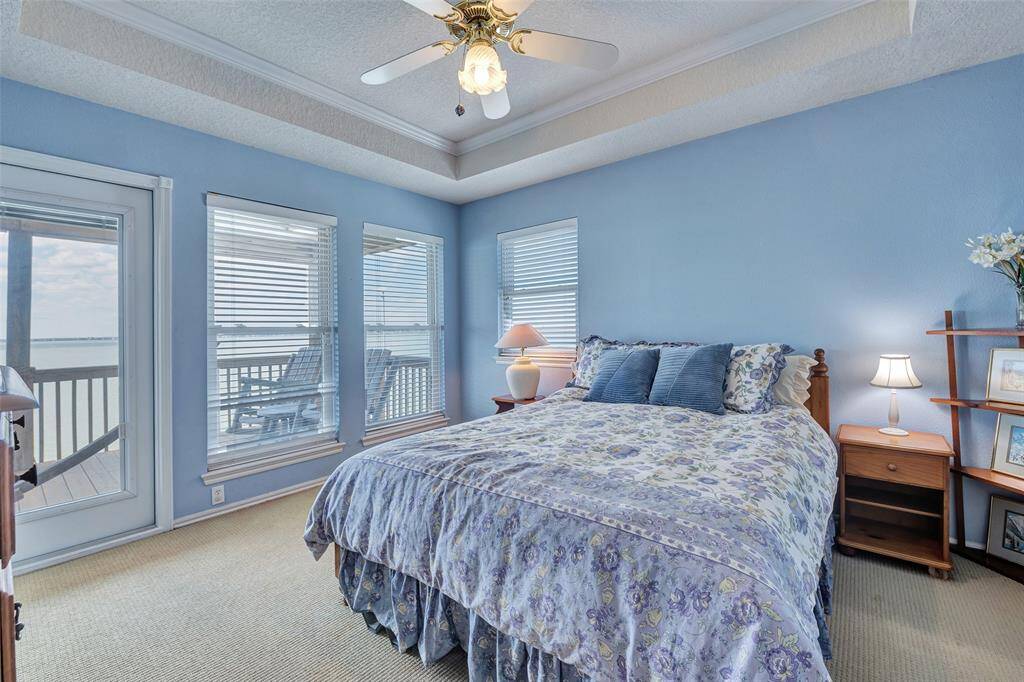 Wake up to stunning water views in this light-filled guest room featuring direct access to the balcony, tray ceiling detail, and peaceful coastal tones. A perfect retreat for visitors or family.