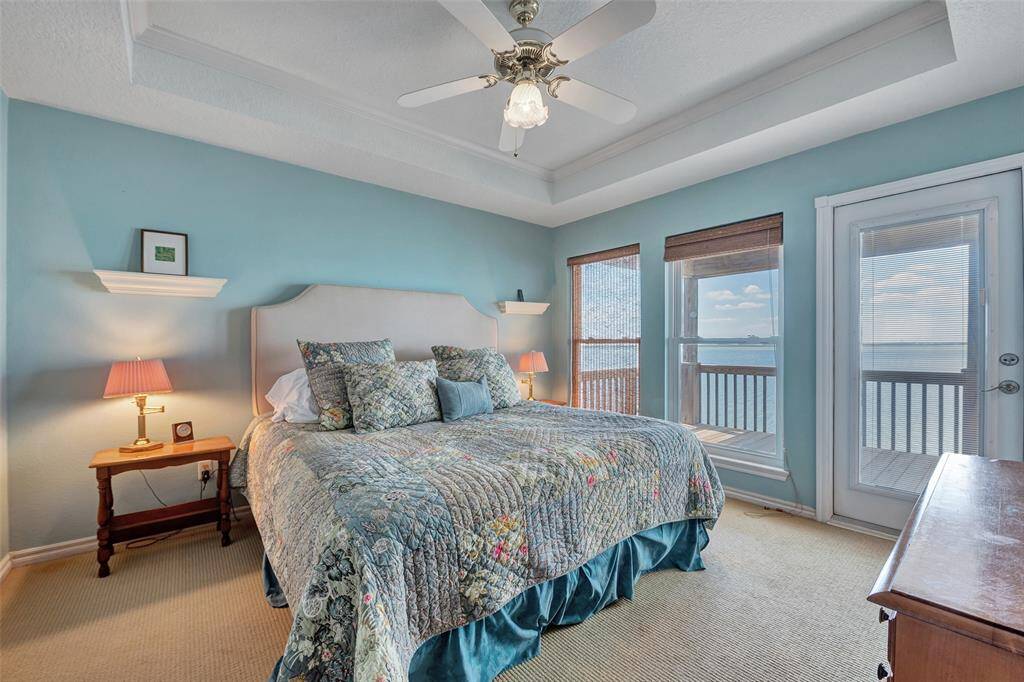 Wake up to panoramic water views in this tranquil primary bedroom, featuring a tray ceiling, soft coastal hues, and direct balcony access. A private retreat with front-row seats to every sunrise.