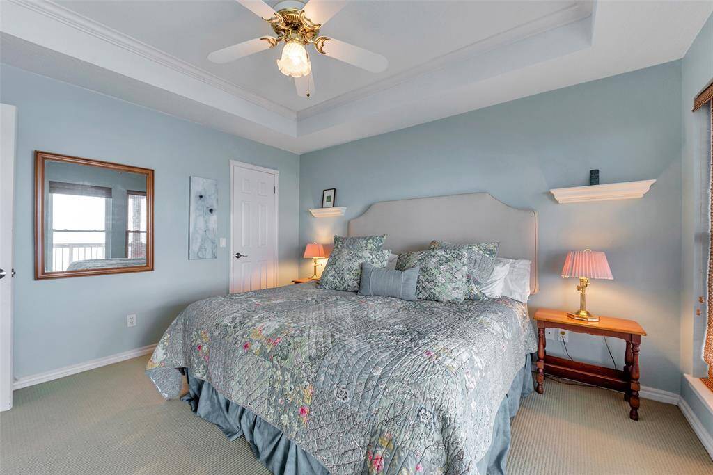 This carpeted primary suite features a ceiling fan for added comfort and a tranquil palette that enhances the restful vibe.
