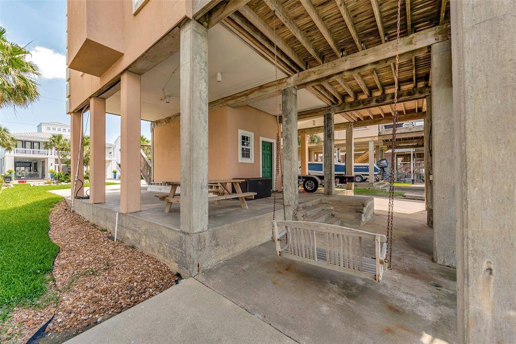 The ground level includes a covered deck with a porch swing and picnic table, plus a carport with space for parking and storage.