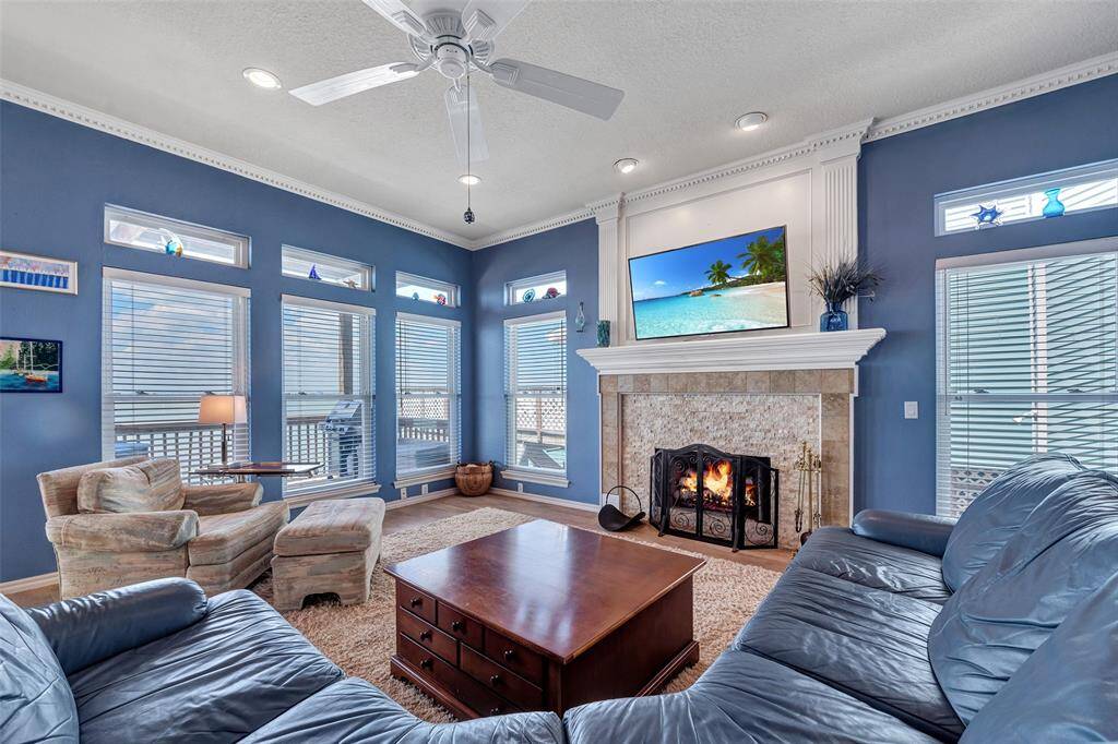 Tall ceilings, crown molding, and a wall of bay-facing windows make this living room feel open and inviting. With a wood-burning fireplace and easy deck access, it’s the perfect spot to unwind or gather with friends.
