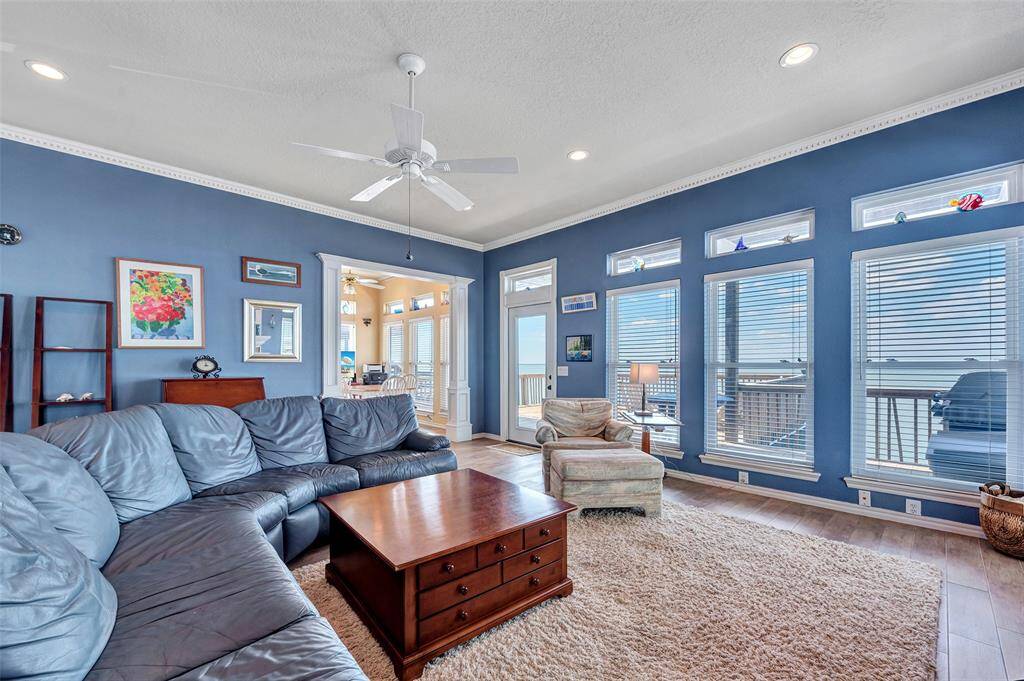 Rows of bay-facing windows fill this space with sunshine and fresh coastal vibes, while wood-look tile plank flooring adds warmth and style. Whether you’re lounging on the couch or heading out to the deck, the bay is always in view.