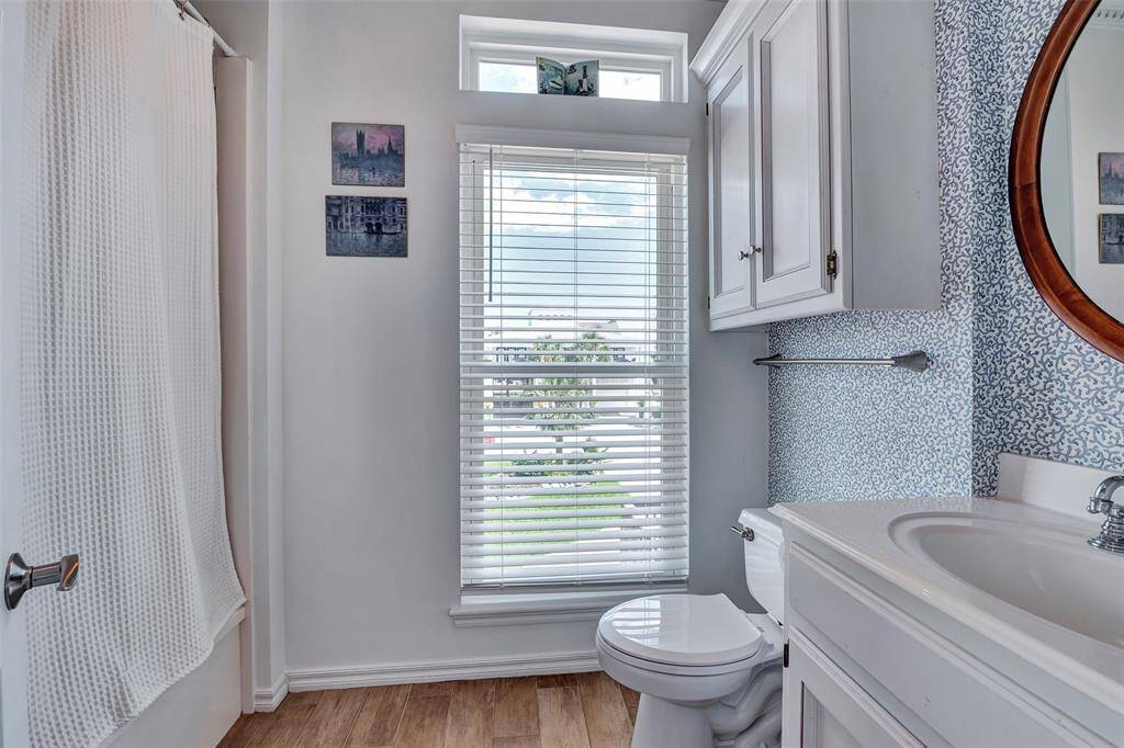 Charming first-floor bathroom features natural light, a full tub/shower combo, and crisp blue accents for a bright, coastal feel. Perfect for guests or convenient access from the main living area.
